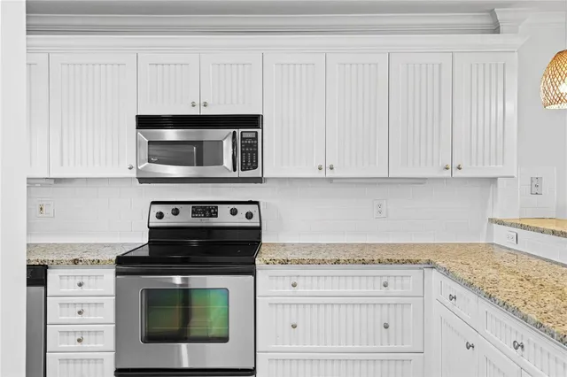 a kitchen with granite countertop white cabinets and stainless steel appliances