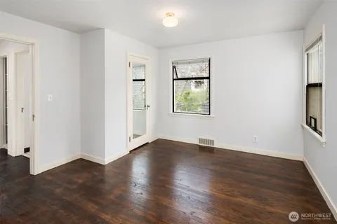 an empty room with wooden floor and windows