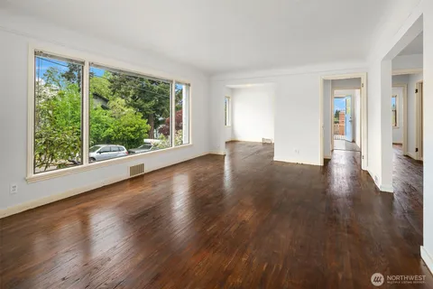a view of a big room with wooden floor garden view and windows