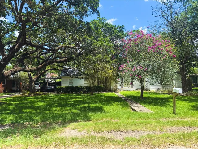 a view of a house with a big yard and large trees