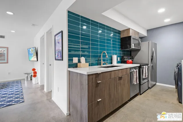 a kitchen with stainless steel appliances kitchen island granite countertop a refrigerator and a sink