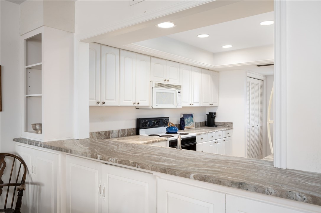 1870 Bay Road, Unit 213G Vero Beach, FL 32963 - Photo 9 of 36 a kitchen with granite countertop white cabinets and white appliances