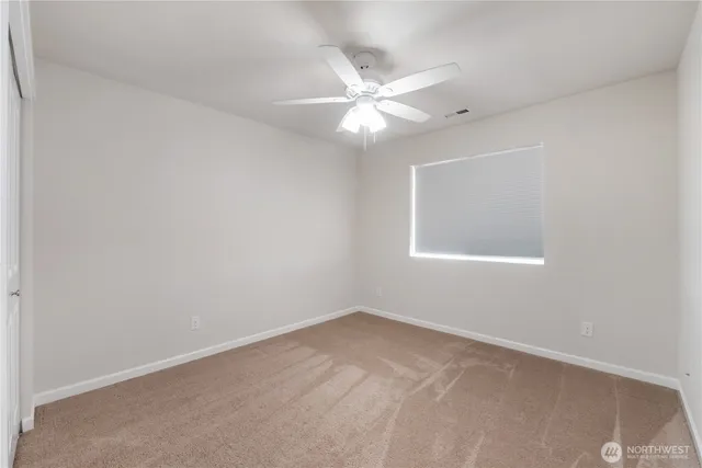 an empty room with a window and a fan