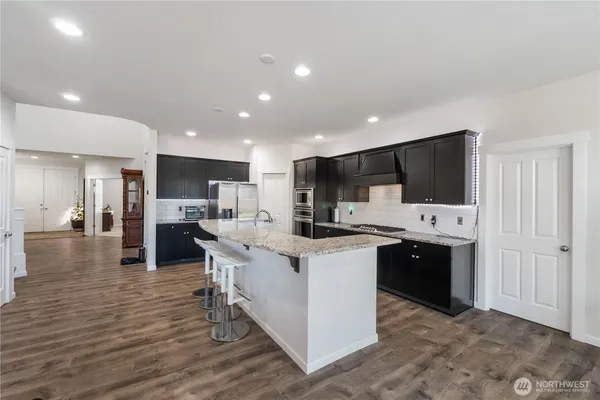 a kitchen with stainless steel appliances kitchen island granite countertop a stove and a sink