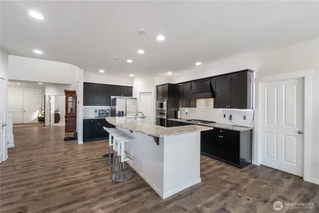a kitchen with stainless steel appliances kitchen island granite countertop a stove and a sink