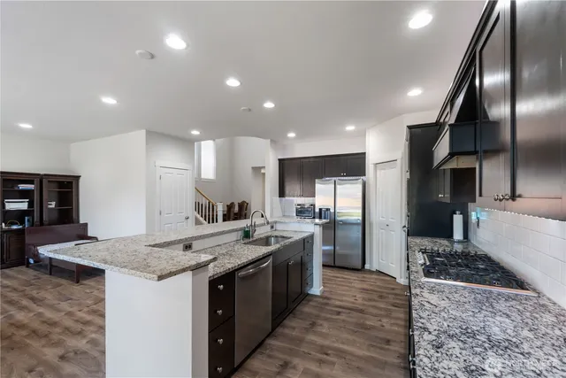 a kitchen with stainless steel appliances granite countertop a stove a sink a refrigerator and a oven