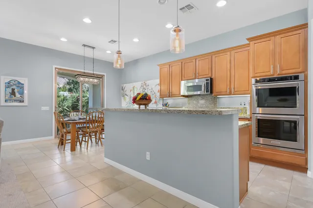 a kitchen with kitchen island granite countertop a stove a microwave a sink a dining table and chairs with wooden floor