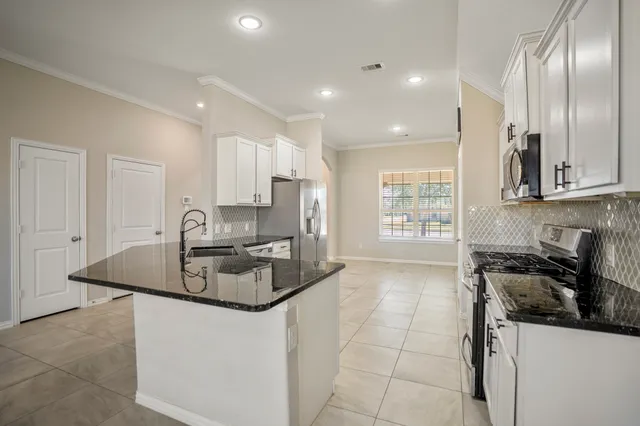 a kitchen with stainless steel appliances granite countertop a sink a stove and a refrigerator