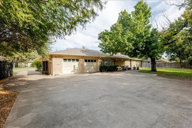 a front view of a house with a yard and a large tree