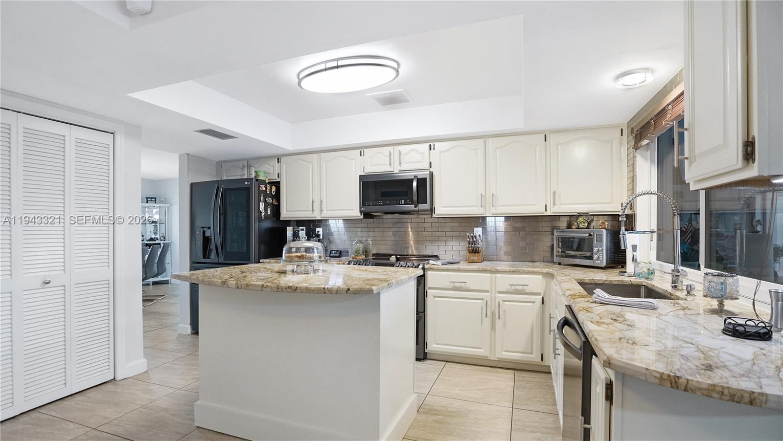 5921 Southwest 17th Street Plantation, FL 33317 - Photo 15 of 53 a kitchen with stainless steel appliances kitchen island granite countertop a stove top oven a sink dishwasher a refrigerator and white cabinets with wooden floor