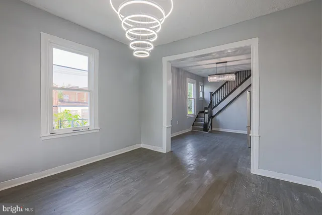 an empty room with wooden floor chandelier and windows