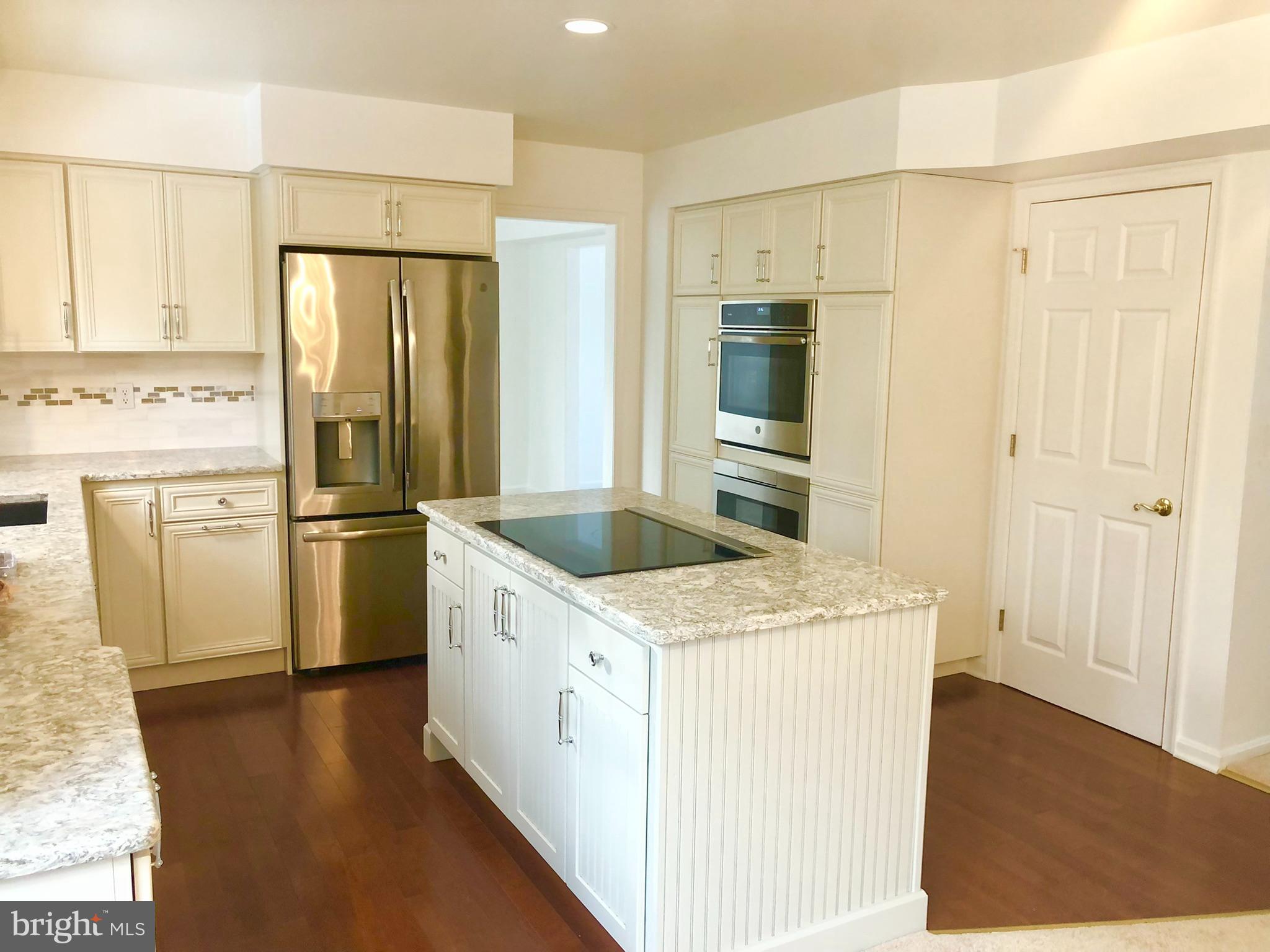 359 Freshfield Lane Arnold, MD 21012 - Photo 8 of 22 a kitchen with a sink a refrigerator a stove and white cabinets with wooden floor
