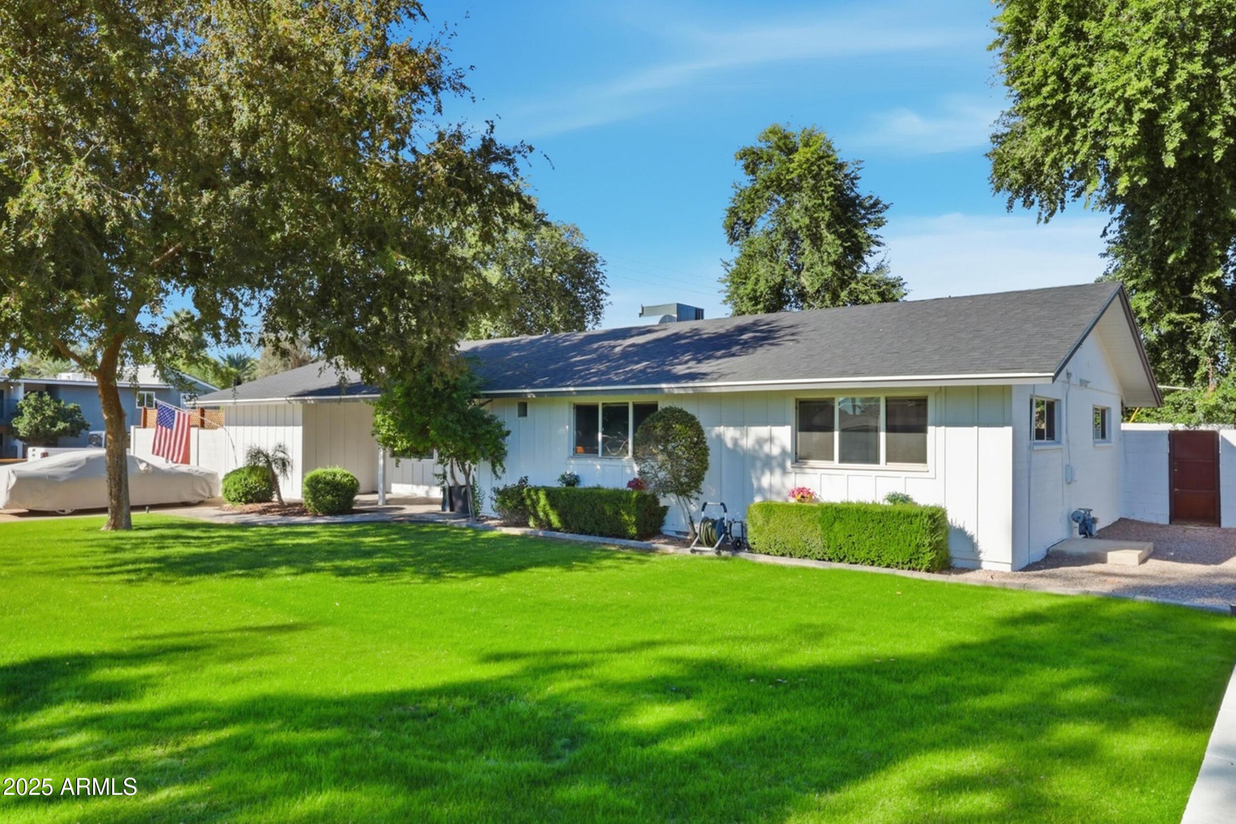 a front view of a house with a garden and trees