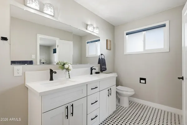 a bathroom with a toilet sink double vanity and mirror