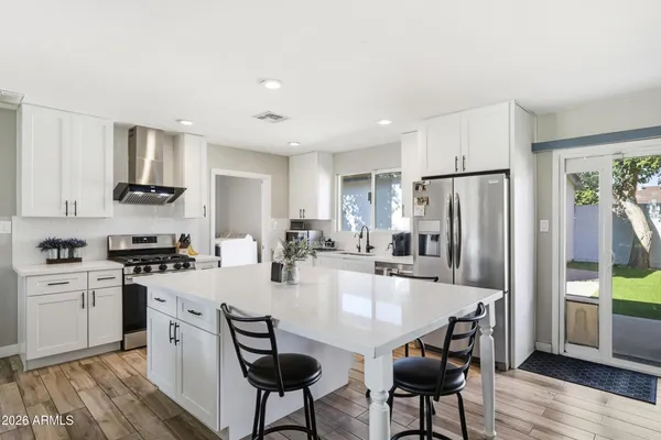 a kitchen with stainless steel appliances granite countertop a stove a refrigerator a kitchen island a table and chairs