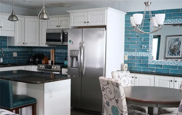 a kitchen with stainless steel appliances granite countertop a sink a microwave a refrigerator and a stove