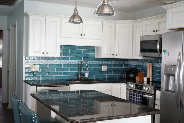 a kitchen with stainless steel appliances granite countertop a sink a stove and cabinets