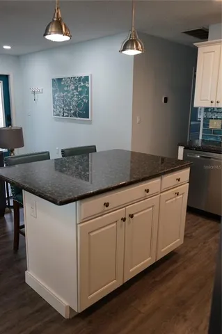 a kitchen with granite countertop a sink cabinets and wooden floor