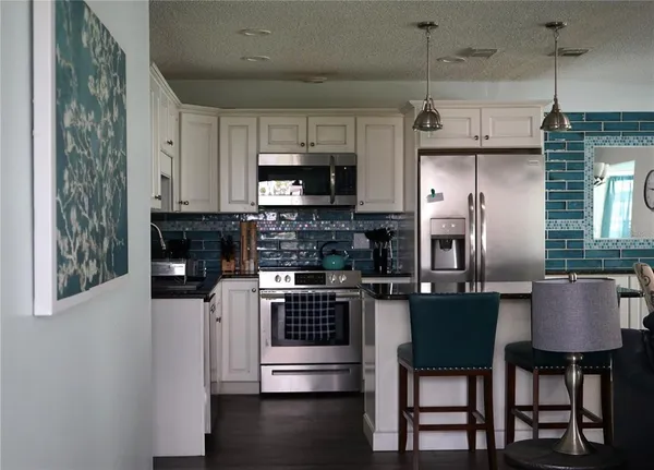 a kitchen with stainless steel appliances granite countertop a stove a microwave a sink and a refrigerator