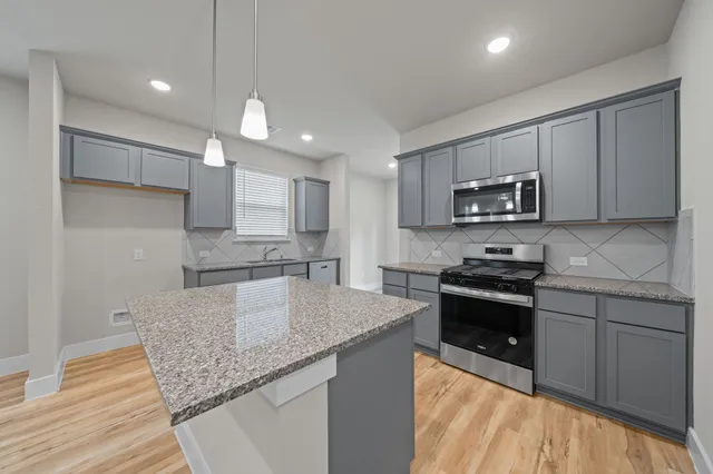 a kitchen with kitchen island granite countertop a stove sink microwave and cabinets