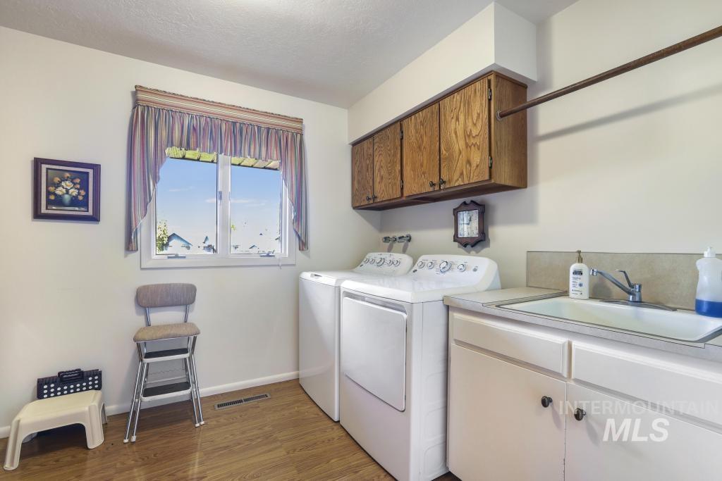 2018 Rancho Vista Drive Twin Falls, ID 83301 - Photo 37 of 50 Dedicated laundry space featuring a utility sink, wood-finish flooring, overhead cabinetry, and a full-size window
