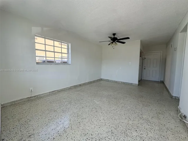 an empty room with a window and a ceiling fan