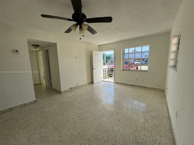 an empty room with windows and fan
