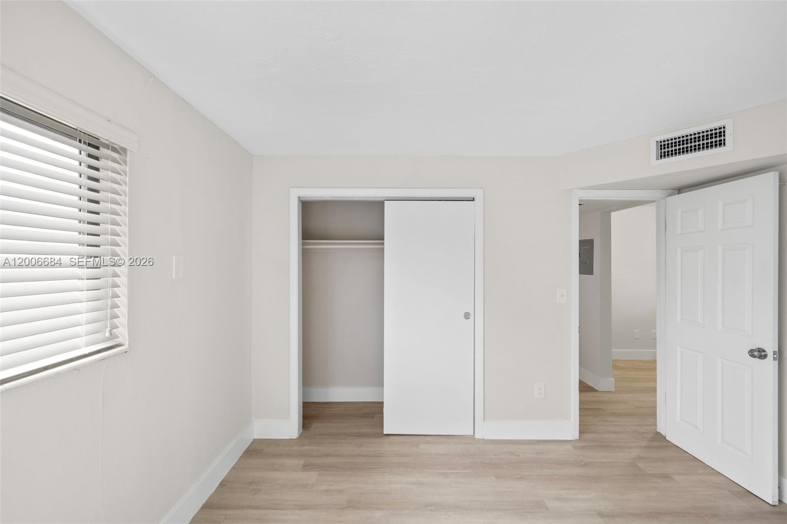 1310 West 29th Street, Unit 22 Hialeah, FL 33012 - Photo 11 of 16 an empty room with wooden floor and windows