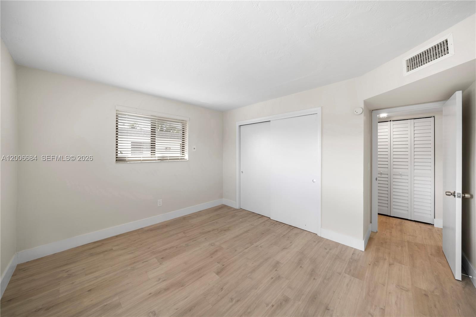 1310 West 29th Street, Unit 22 Hialeah, FL 33012 - Photo 10 of 16 an empty room with wooden floor and windows