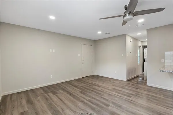 an empty room with wooden floor a ceiling fan and staircase