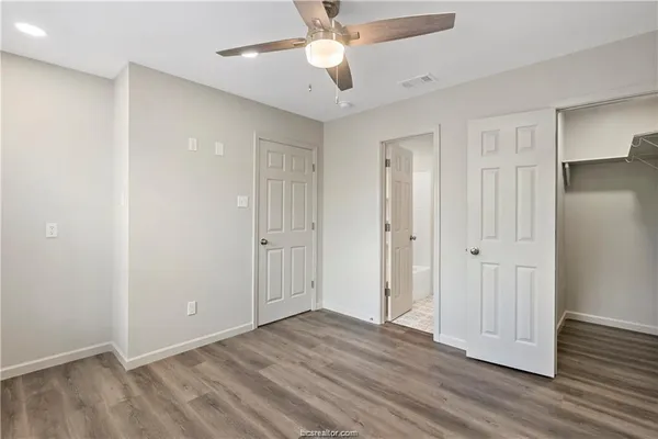 an empty room with wooden floor and a ceiling fan