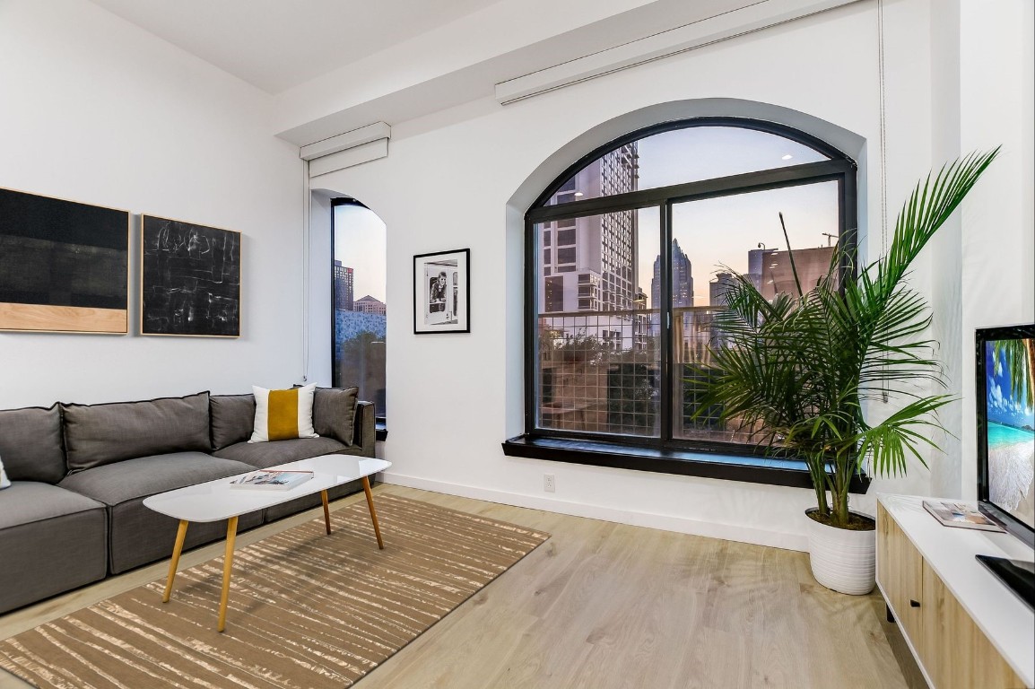 a living room with furniture a flat screen tv and a large window