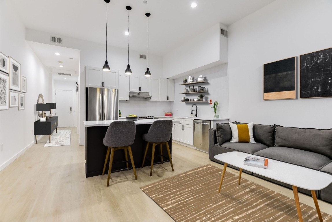 507 Sabine Street, Unit 303 Austin, TX 78701 - Photo 6 of 28 a living room with furniture a rug kitchen view and a chandelier