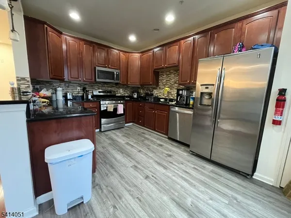 a kitchen with kitchen island granite countertop wooden floors wooden cabinets a sink and appliances