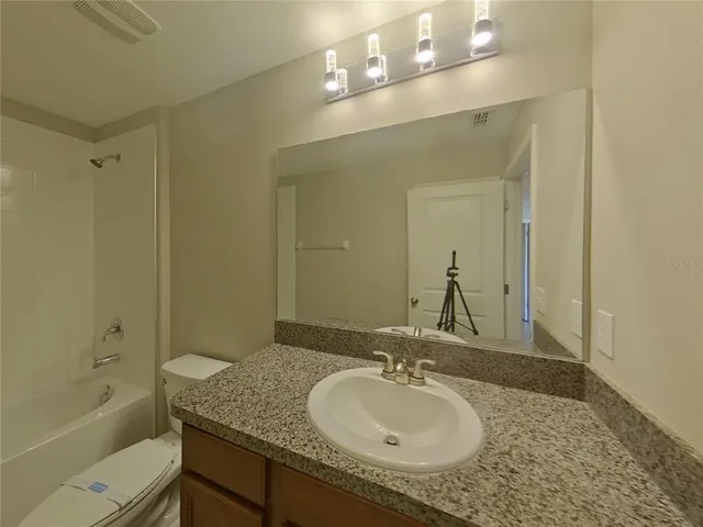 a bathroom with a granite countertop toilet a sink and shower