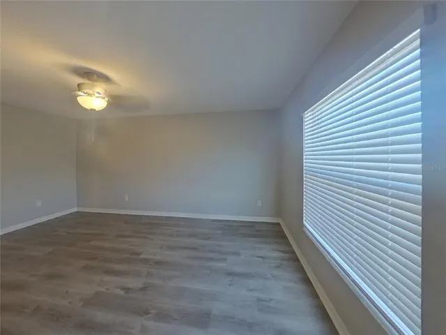 a view of an empty room with wooden floor and window
