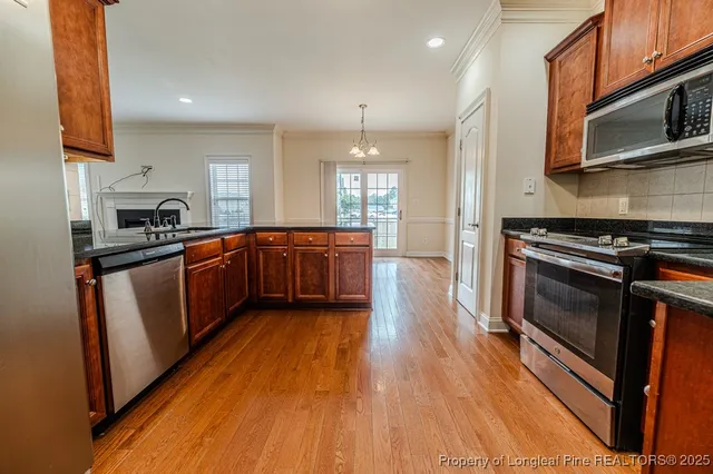 a kitchen with stainless steel appliances granite countertop wooden cabinets a stove top oven a sink and dishwasher