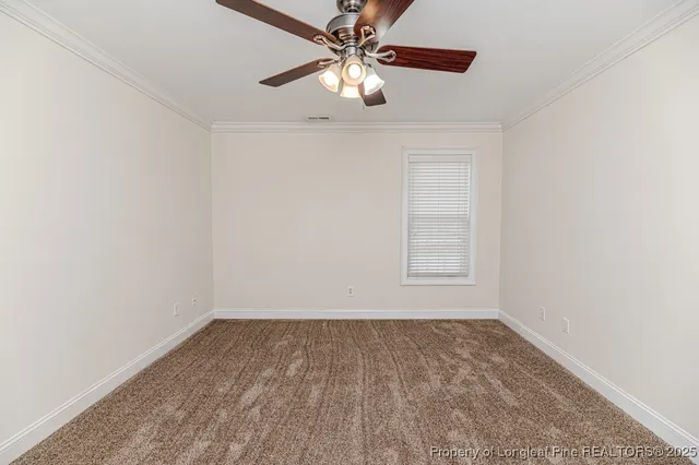 an empty room with a chandelier fan and windows