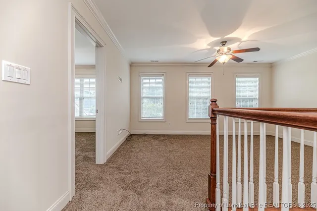 an empty room with chandelier fan and windows