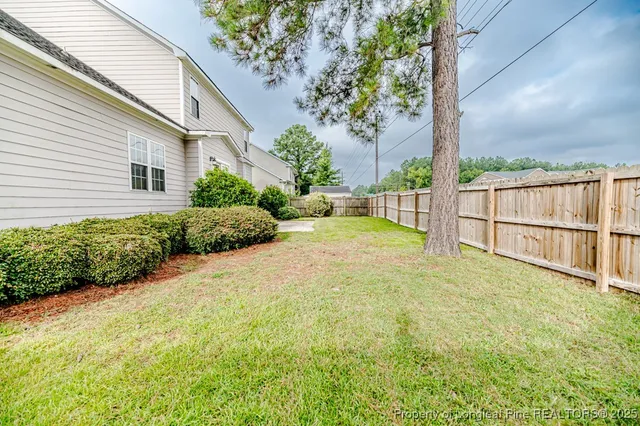 a backyard of a house with table and chairs and wooden fence