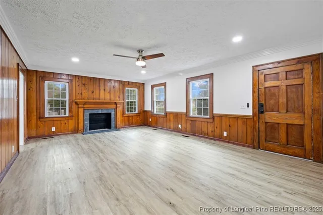 an empty room with wooden floor fireplace and windows