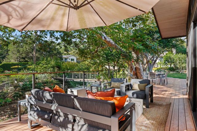 a view of a patio with table and chairs potted plants and large tree