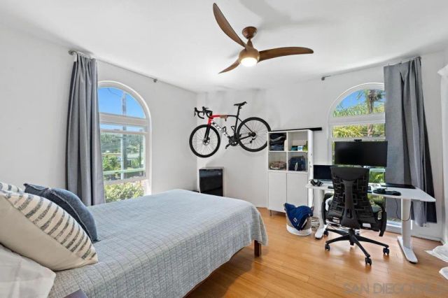 a bedroom with a bed a flat screen tv and a large window with wooden floor