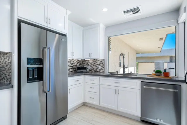 a kitchen with white cabinets and refrigerator