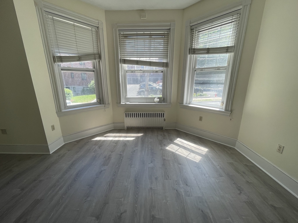 96 St Paul Street, Unit 2 Brookline, MA 02446 - Photo 3 of 14 an empty room with wooden floor and windows