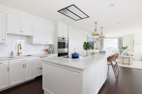 a kitchen with a sink dishwasher a stove a dining table and chairs with wooden floor