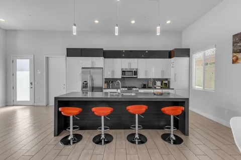 a kitchen with stainless steel appliances granite countertop a sink a stove a refrigerator a microwave oven with white cabinets and wooden floor