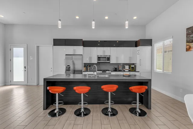 a kitchen with stainless steel appliances granite countertop a sink a stove a refrigerator a microwave oven with white cabinets and wooden floor