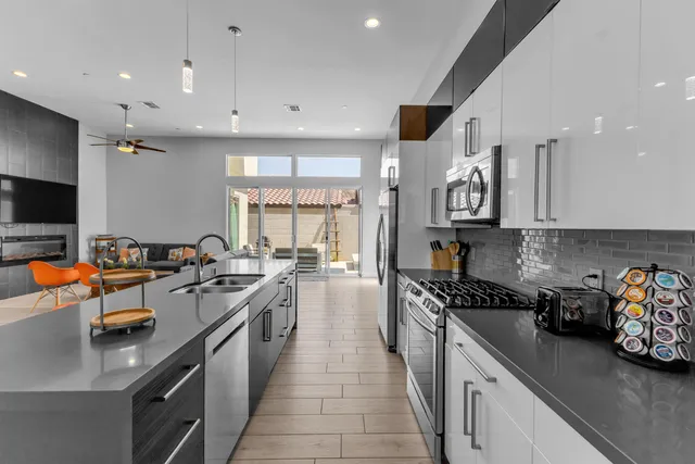 a kitchen with stainless steel appliances granite countertop a refrigerator a stove and a sink with wooden floor