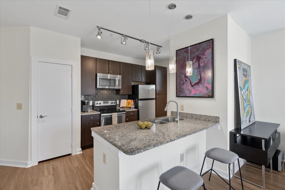 1900 Barton Springs Road, Unit 5001 Austin, TX 78704 - Photo 7 of 34 a kitchen with granite countertop kitchen island stainless steel appliances microwave stove refrigerator and wooden floor